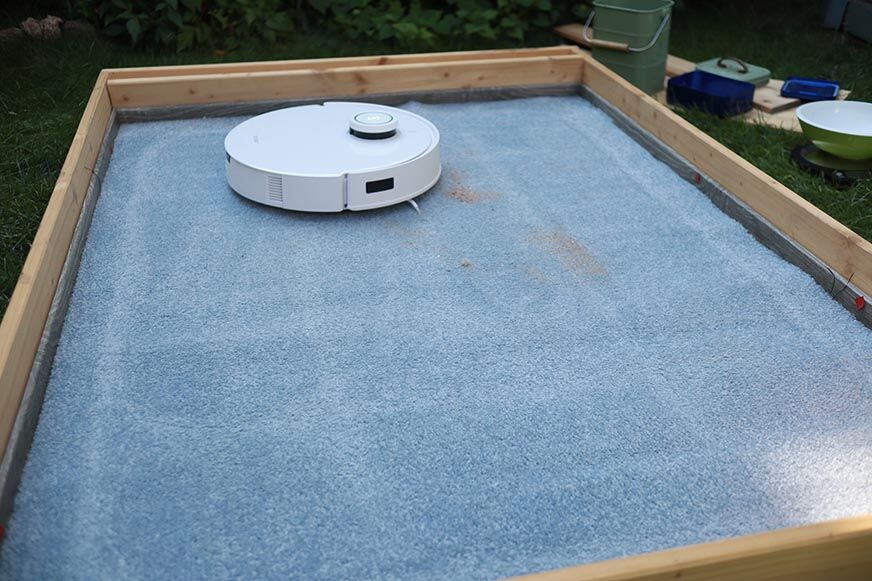 Ecovacs Deebot T10 reinigt Sand auf einem Teppich im Saugtest.